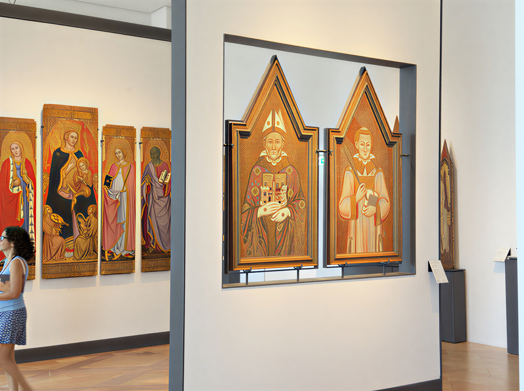 Photographie de la Galleria Nazionale dell'Umbria montrant des panneaux sculptés de la Renaissance italienne, avec des visiteurs captivés par l'art, dans un cadre moderne et lumineux.