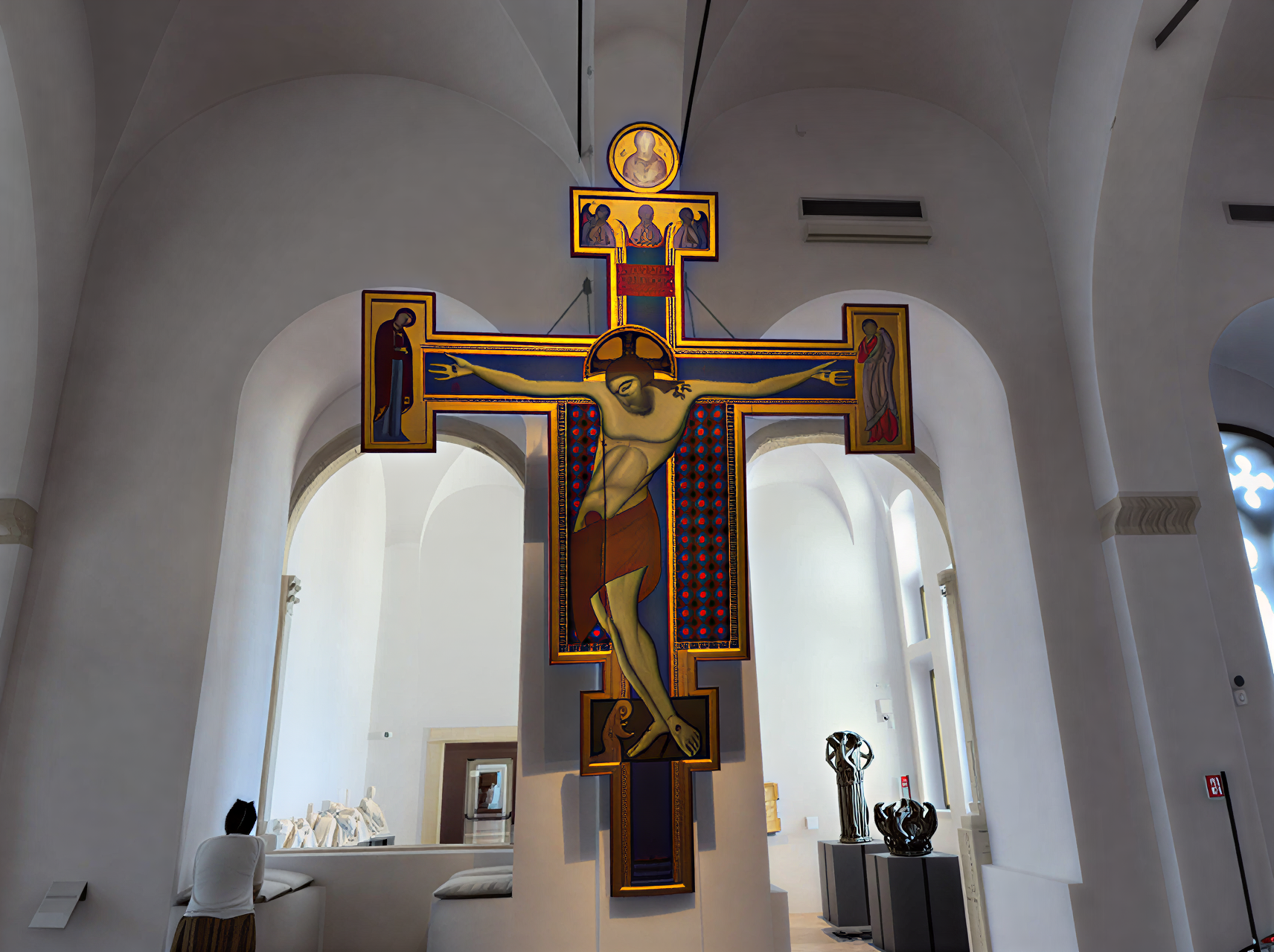 Photographie d'une croix monumentale de la Renaissance dans la Galleria Nazionale dell'Umbria, Pérouse, Italie, avec un visiteur en contemplation.